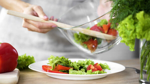 Lady putting fresh salad on her plate, going to have lunch, healthy eating