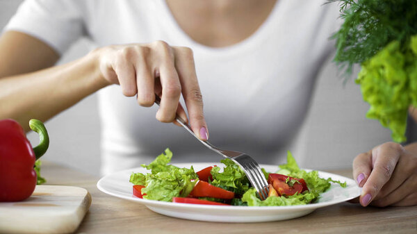 Young lady taking tomato salad fork from dinner plate, healthy snack, vitamins