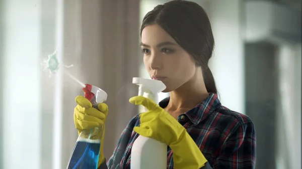 Huisvrouw sproeien verschillende glazenwassers op glas, brengen van huis om te bestellen — Stockfoto