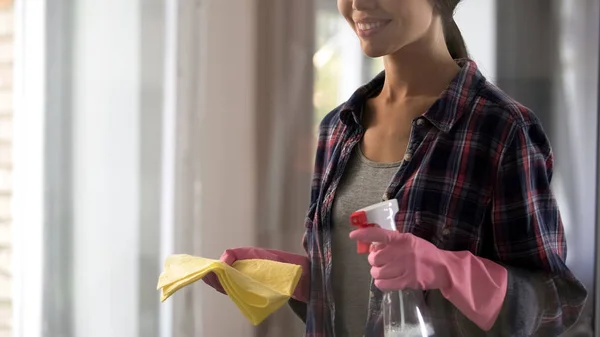 Молодая женщина готовится к генеральной уборке, держа спрей и желтый ковер — стоковое фото