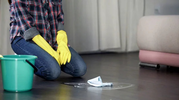 Hotel maid kneeling feeling tired of washing dirty floor stains, sanitizer