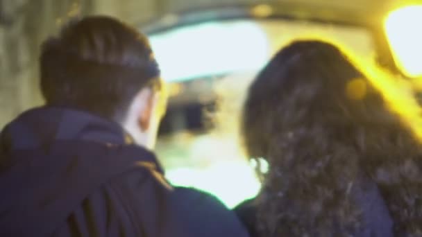 Пара подростков медленно прогуливаются по вечернему городу, вид сзади, прогулка — стоковое видео