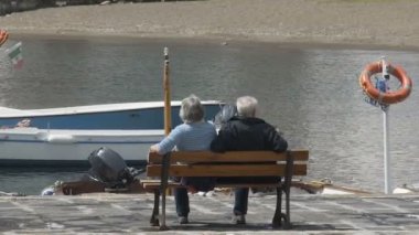 Ischia, İtalya - Temmuz 2014 yaklaşık: İnsanlar adada. Deniz araçları, dalgalar kıyıya haddeleme ile defne üzerinde seyir iskele üzerinde bankta yaşlı çift