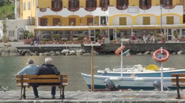 Ischia, İtalya - Temmuz 2014 yaklaşık: İnsanlar adada. Ischia street teknelerle, bay genelinde ile ilgilenen bankta oturan yaşlı çift gezisi