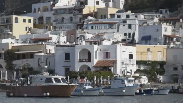 Casas de verano construidas hacia arriba frente al puerto con barcos atracados por muelle en un día soleado — Vídeo de stock