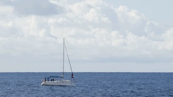 Łódź ze zwiniętymi żagle żeglarstwo przez błękitne morze pod zachmurzonym niebie, Rekreacja — Wideo stockowe