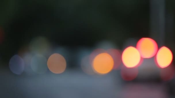 Circulation routière dans la ville du soir, taches de lumière floue se transformant en phares de voiture 