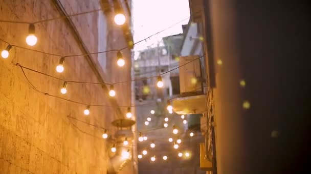 Narrow street illuminated with light bulbs, festive mood in night city, design — Stock Video