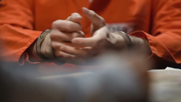 Więzień rozgrzewa nadgarstków, w kajdankach, daje dowody, detektyw piśmie świadectwo — Wideo stockowe