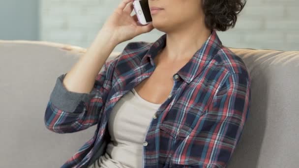 Jeune femme parlant au téléphone à la maison canapé, communication familiale, technologie — Video