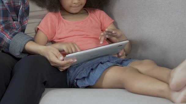 Χαριτωμένο σγουρά κορίτσι που παίζει το παιχνίδι στο tablet σπίτι, τη διασκέδαση με τη μητέρα, ανατροφή των παιδιών — Αρχείο Βίντεο
