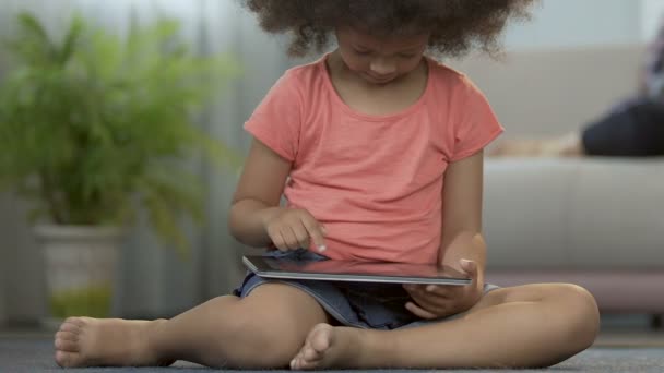 Menina pequena jogando jogos no tablet sentado no chão em casa, educação pré-escolar — Vídeo de Stock