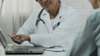 Gülümseyen jinekolog ultrason görüntü dizüstü bilgisayarda hamile hastasını gösterilen.