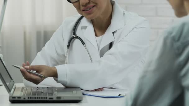 Ginecólogo sonriente mostrando imagen de ultrasonido en la computadora portátil a su paciente embarazada — Vídeo de stock