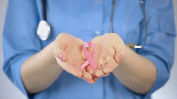 Růžovou stuhou, ležící v dlaních ženského lékaře, osvětovou kampaň proti rakovině prsu — Stock fotografie