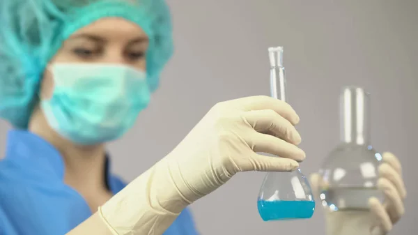 Женщина-химик держит трубки с жидкостью, работает в лаборатории по вакцинации — стоковое фото