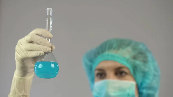 Trabajadora de laboratorio sosteniendo tubo con líquido azul en la mano, biología ciencia —  Fotos de Stock