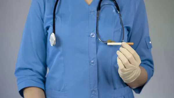 Médecin femme tenant la cigarette dans la main, avertissement de cancer, mauvaise dépendance — Photo