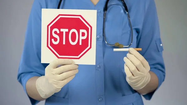 Enfermeira hospitalar segurando stop sign e cigarro, prevenindo estilo de vida insalubre — Fotografia de Stock