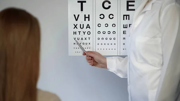 Mujer leyendo durante el examen de la vista clínica, visita oftalmólogo —  Fotos de Stock