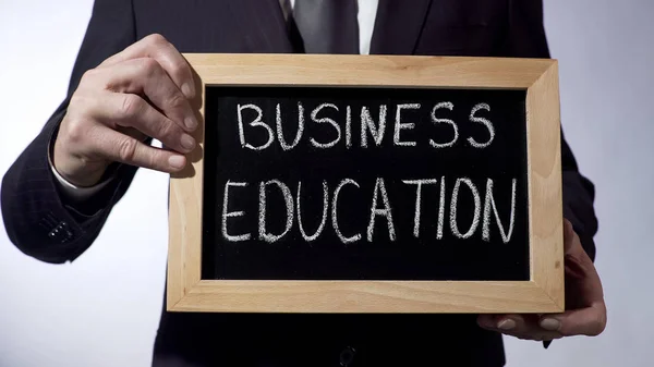 Бізнес-освіта написана на дошці, бізнесмен тримає знак, майбутнє — стокове фото