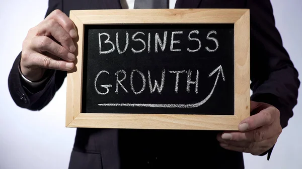Зростання бізнесу, написане на дошці, чоловік у костюмі тримає знак, успіх — стокове фото