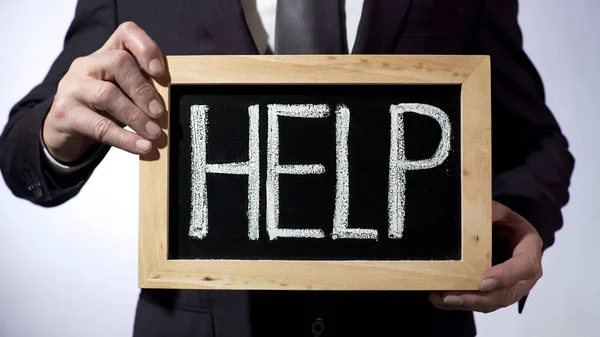 Help written on blackboard, man wearing black suit holding sign, consultation — Stock Photo, Image