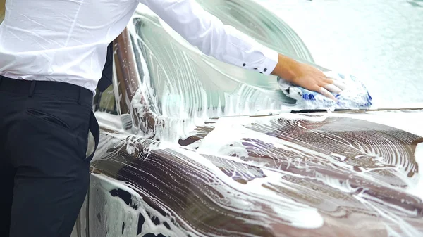 Autista scrupoloso accuratamente lavare parabrezza della sua auto di lusso, lavaggio auto — Foto Stock