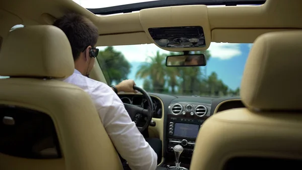 Бізнесмен керує автомобілем і розмовляє по телефону через бездротову гарнітуру, технологія — стокове фото