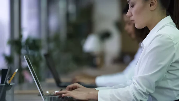 Mooie vrouw typen op laptop, werken op zakelijk project met gerichte gezicht — Stockfoto