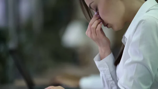 Overwerkt jonge zakenvrouw wrijven van de ogen, moe na een moeilijke dag op het werk — Stockfoto