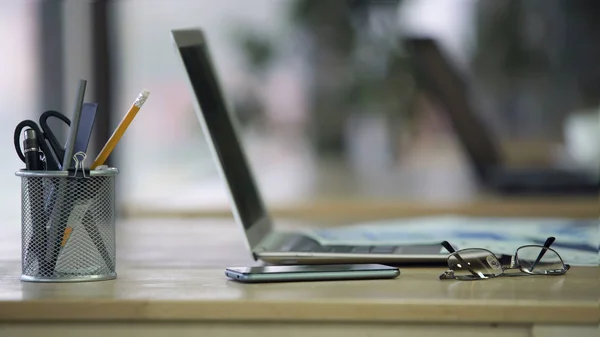Fechar o local de trabalho no escritório da empresa, titular da caneta, óculos, laptop na mesa — Fotografia de Stock