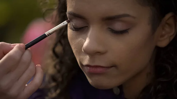 Mujer haciendo maquillaje ojos humeantes, preparando hermosa actriz para el rodaje de películas — Foto de Stock