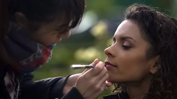 Maquillaje artista aplicando lápiz labial en los labios modelos, belleza natural de la señora biracial — Foto de Stock