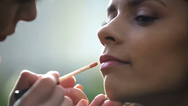 Manos de artista de maquillaje aplicando brillo de labios, preparando hermosa novia para la boda — Foto de Stock