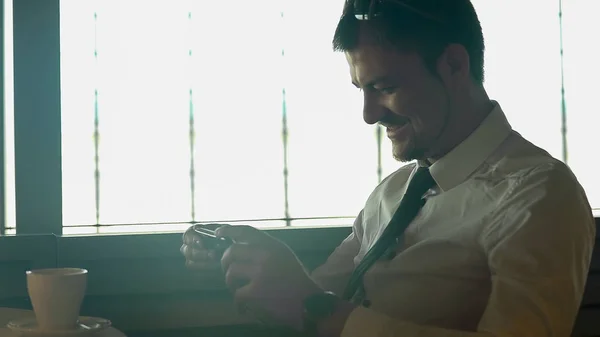 Jeune homme heureux regardant un film sur smartphone dans un café et souriant, gadgets — Photo