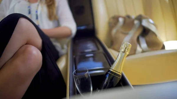 Glamorous woman sitting in expensive car, bottle of champagne and glass closeup — Stock Photo, Image