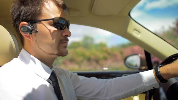 Professional chauffeur of elite taxi driving car, listening to bluetooth headset — Stock Photo, Image