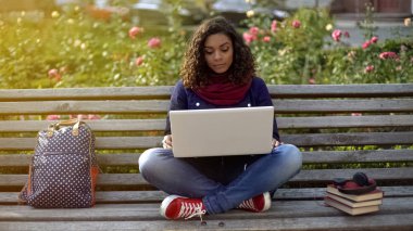 Bankta oturan laptop kamera üzerinden arkadaşlarınızla konuşurken ciddi kız öğrenci