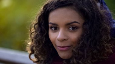 Kamera ve içtenlikle, gülümseyen yüz için yakın çekim poz güzel biracial kadın