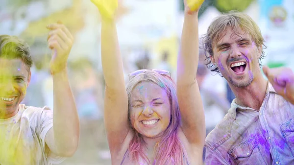 Emocionados jóvenes lanzando polvo de colores en el aire, brillando de felicidad — Foto de Stock