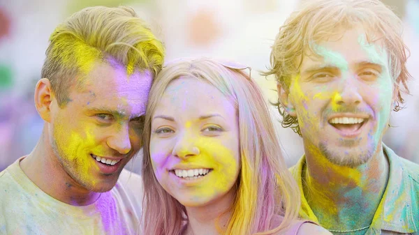Ενθουσιασμένος πρόσωπα των όμορφη νέους που καλύπτονται στα χρώματα που χαμογελά στη φωτογραφική μηχανή — Φωτογραφία Αρχείου