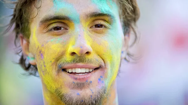 Молодий чоловік з кольоровим порошком на обличчі крупним планом, святкування літнього фестивалю, веселощі — стокове фото