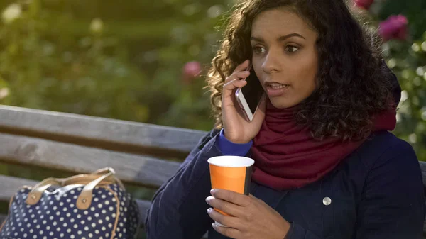Atractiva mujer de raza mixta hablando por teléfono y tomando café al aire libre — Foto de Stock
