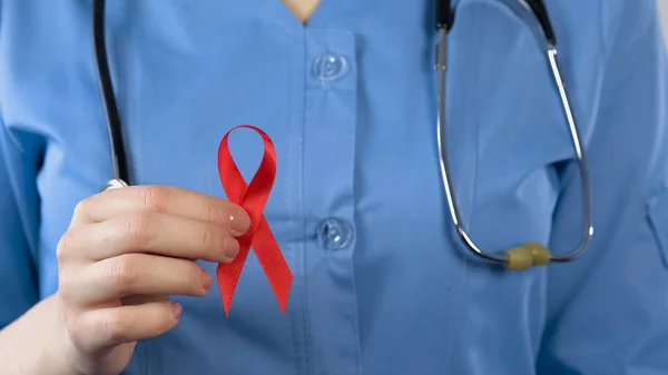 Doctora que muestra el primer plano de la cinta roja, símbolo internacional de conciencia sobre el sida — Foto de Stock
