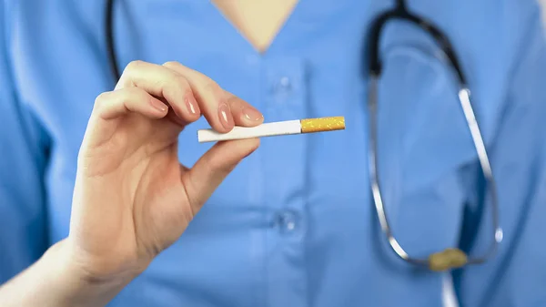 Terapeuta feminina mostrando cigarro, alertando sobre os perigos do tabagismo para a saúde — Fotografia de Stock