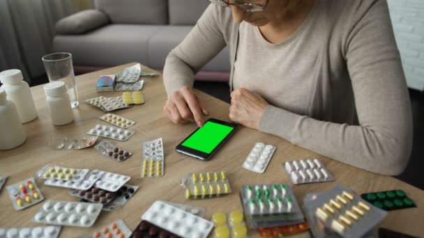 Äldre kvinna rullning smartphone, online medicin consulting, grön skärm — Stockvideo