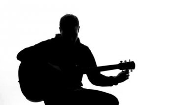 Genç adam siluet ayarlama gitar, profesyonel yazma şarkı, müzik hobi.