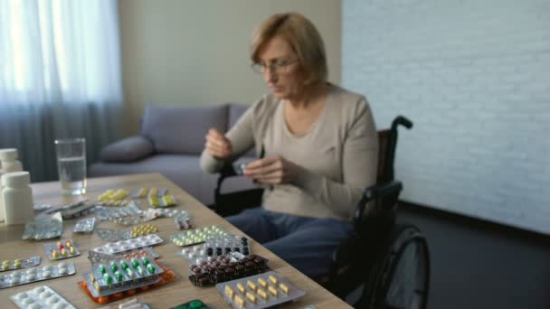 Инвалид в инвалидной коляске пьет таблетки с водой, восстанавливается, ухаживает дома — стоковое видео