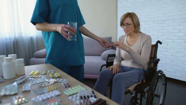 Enfermeira do hospital que dá medicamentos a doentes do sexo feminino na rotina de tratamento da cadeira de rodas — Vídeo de Stock